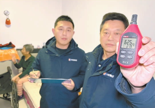 供热管家段勇(右一)和同事入户测量,居民家室温21.9℃达标。